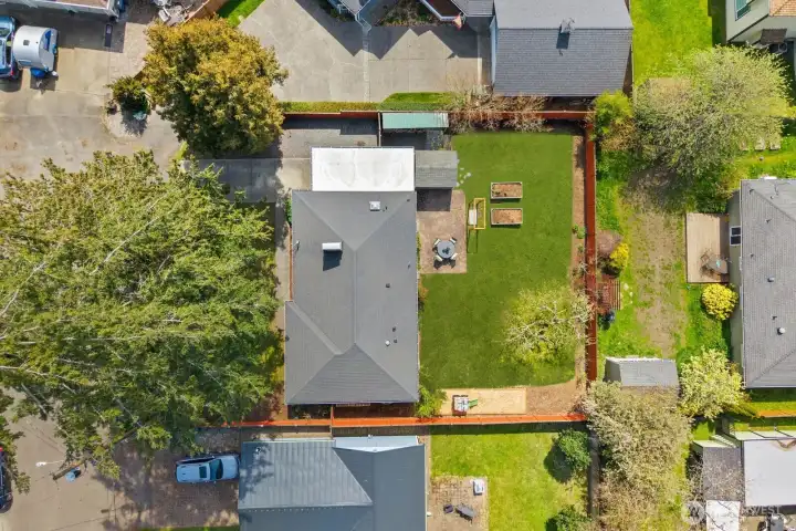 Aerial views of the property and surrounding neighborhood showcase the fully fenced backyard, open lawn, garden beds, and detached storage structure. Elevated perspectives highlight the home's residential setting, mature trees, and generous outdoor space within the established community.