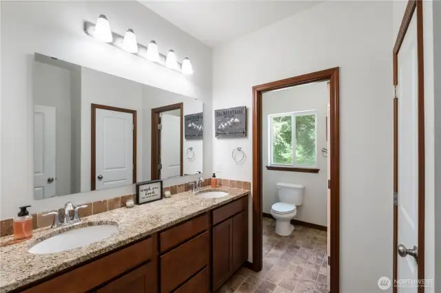 Full guest bathroom with dual sinks and a shower/tub combo.