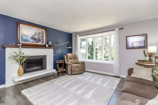 Bright and airy upstairs living room with a large bay window, enhancing this East Hill home’s open-flowing design.