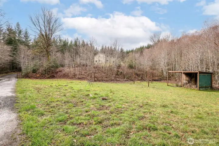 Lower pasture area with house behind trees in center of photo