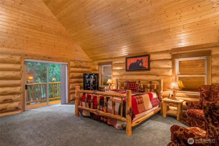 pacious primary suite with vaulted tongue-and-groove ceilings, custom log craftsmanship, and private deck access overlooking the evergreens.