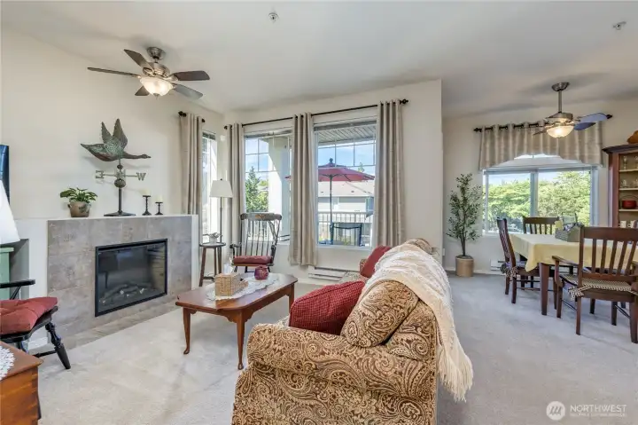 Light-filled corner unit featuring an inviting electric fireplace and comfortable ceiling fans throughout.