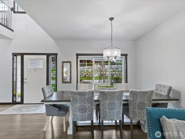 This inviting dining area offers plenty of space for gatherings, featuring elegant lighting, large windows that bring in natural light, and an open flow to the kitchen, perfect for entertaining.