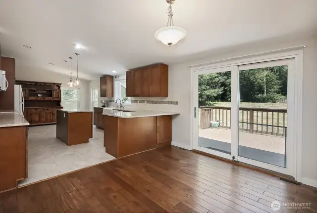 Let's go check out the Chef's kitchen with tiled flooring.  Plenty of room for stools at the breakfast bar/counter. Sliding glass doors lead to your expansive Trex deck.