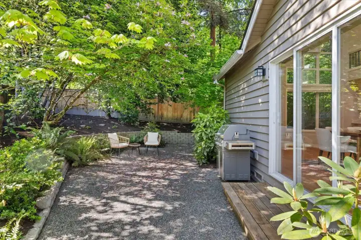 Tranquil patio is surrounded by mature, low maintenance greenery.