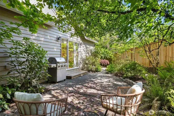 Tranquil patio is surrounded by mature, low maintenance greenery.