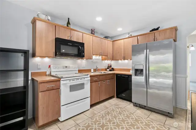 A fully equipped kitchen has a Stainless Steel fridge, dishwasher, stove and fridge and easy to care for tile flooring.