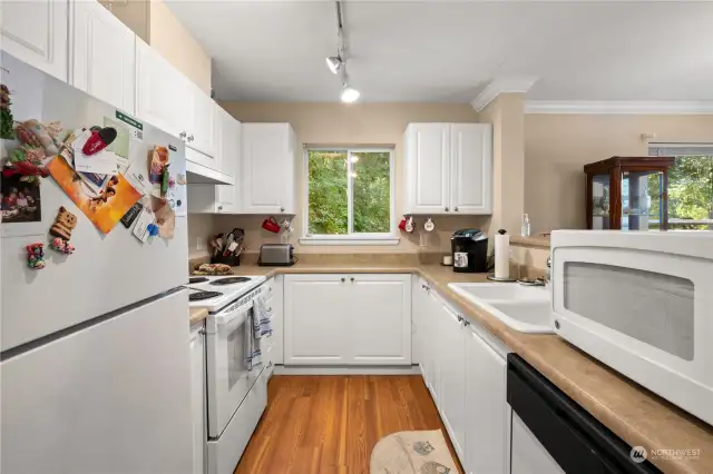Galley style kitchen with ample storage and prep space. Double, deep sink for your convenience. Open ledge area above cabinets for additional kitchen and cooking necessities. Window with garden view.