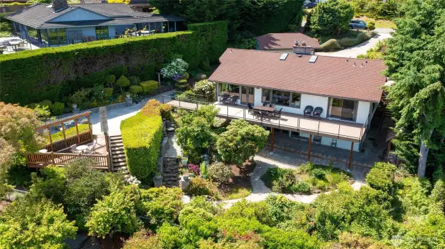 the large terraced back yard is heavily landscaped with flowers, roses and fruit trees