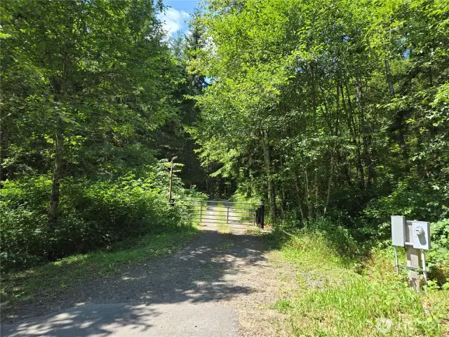 Neighbor to the West. Their gate as they drive thru this property to the West. You can walk in to view the property,  but we don't have gate code at this time.