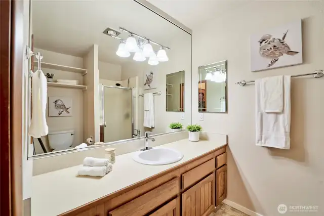 Here's the en-suite bathroom off the primary bedroom. It's quite spacious and offers newer vinyl flooring and updated light fixtures. There's plenty of space for a double vanity if a future remodel is in the plans.