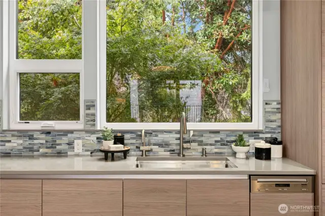 New solid surface quartz countertops were added plus a new custom-tiled backsplash. Lovely kitchen sink view out to the trees and greenery in the back area.