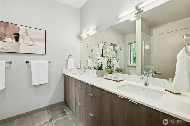 The primary suite bathroom with dual sinks, an oversized tiled shower and radiant heated floors.