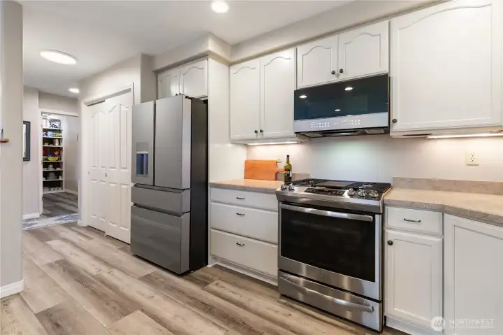 A well-designed kitchen with the pantry next to the refrigerator. You can see the door to den beyond.