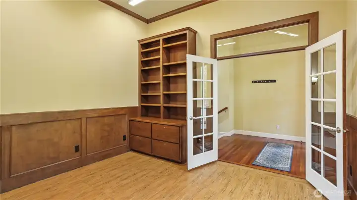 Elegant den with double-door entry and rich wood wainscoting and built-in shelving—perfect for a home office.