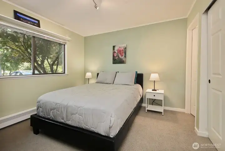 Main level bedroom with generously sized window that looks out upon mature landscaping including a Japanese Maple.