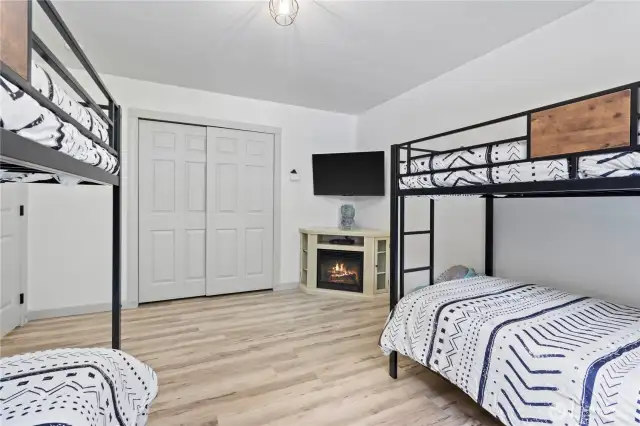 This spacious bunk room is not only kid-friendly but also thoughtfully equipped with comfort and entertainment in mind. Featuring two sturdy metal bunk beds, a built-in electric fireplace for added ambiance, and a mounted flat-screen TV, it’s the perfect retreat for guests or a playful sleepover haven.