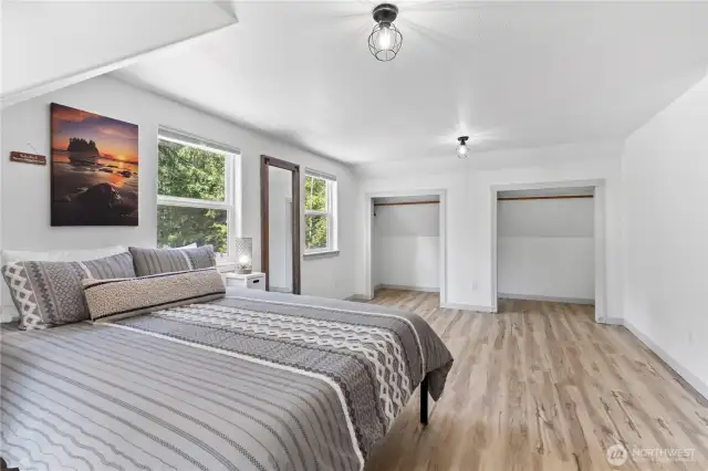 This generously sized primary bedroom features two large closets, providing ample storage and organization. The layout offers room for a seating area or additional furniture, while oversized windows bring in natural light and offer tranquil views of the surrounding greenery.