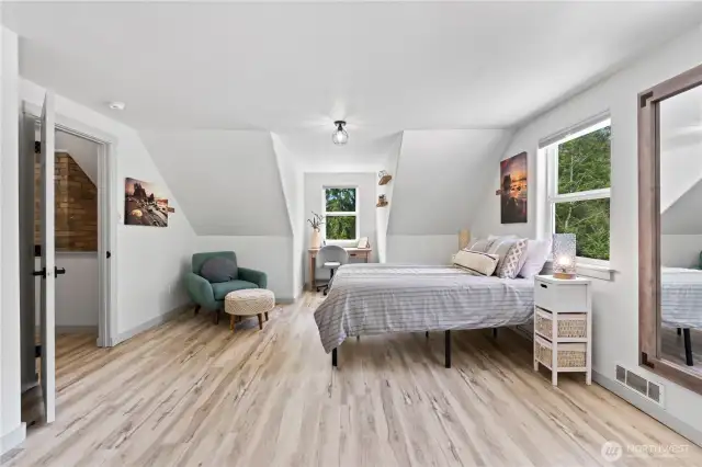 This versatile bedroom includes a built-in reading nook and workspace, perfect for remote work or study. Sloped ceilings add charm while natural light from three windows creates an uplifting atmosphere. A serene and functional space ideal for everyday living.