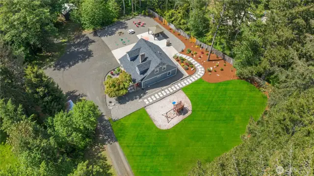 This aerial perspective reveals the full scale and smart layout of this gorgeous property—complete with an expansive green lawn, landscaped walkways, a playground, and ample driveway space for parking or future expansion. Surrounded by trees for privacy, the property offers room to breathe while maintaining a clean, well-kept appearance that’s move-in ready.