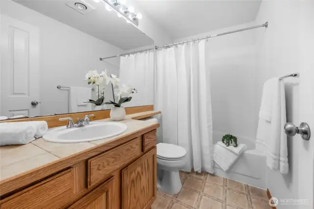 Good size single vanity, ceramic tiled counter, and freshly painted Primary  bedroom bathroom.