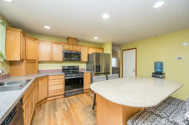 Spacious kitchen with granite island and hardwoods.