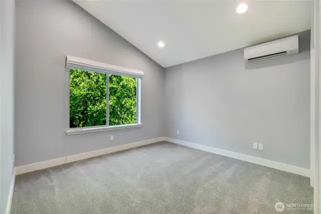 Large third bedroom with vaulted ceilings and a ductless heat pump for customizable comfort. Closet is out of view, far right.