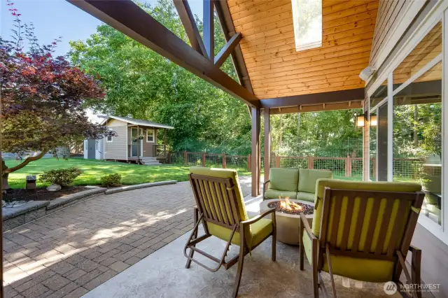 The covered patio allows for year round use and a skylight ensures it never feels too dark. From here you can see the undeveloped space just past the fence which serves as a buffer between houses and provides additional privacy.