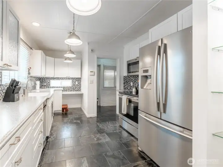 Updated kitchen featuring Corian countertops, tile flooring, and abundant cabinetry