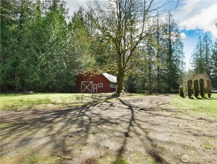 Experience the quintessential Pacific Northwest lifestyle on this country estate. Towering fir trees provide a majestic backdrop for a stylish, functional red bar - the perfect setting for your own horses.