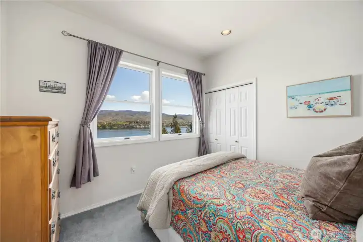 Cozy office or additional sleeping space with a large windows framing scenic lake and mountain views. The space features neutral tones, soft natural light, and a comfortable layout.