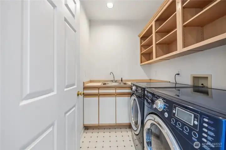 Laundry room with side-by-side washer and dryer, and upper shelving for storage. Clean, functional layout with built-in organization.