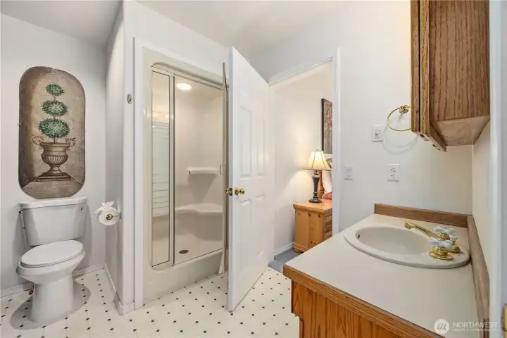Guest/Guest suite attached bathroom with a single-sink vanity, wood cabinetry, and shower. Light finishes and a functional layout create a clean, bright space.
