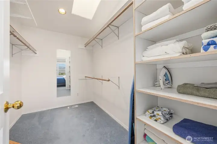 Primary walk-in closet with built-in shelving, hanging rods, and organized storage space. Clean, functional layout with ample room for clothing and accessories.