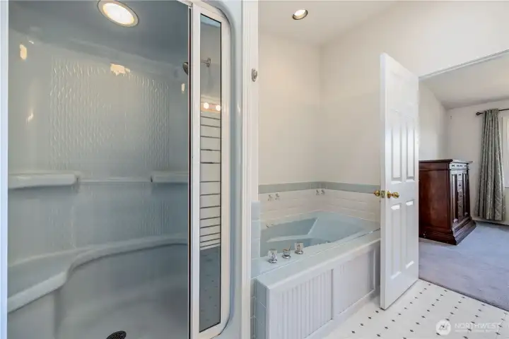 Primary bath featuring a glass-enclosed shower and jetted soaking tub, with bright finishes and a clean, functional layout.