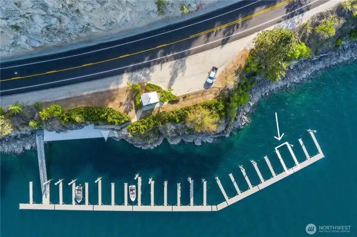 Community waterfront with dock and boat slips extending into the lake, surrounded by mountain views and clear blue water.