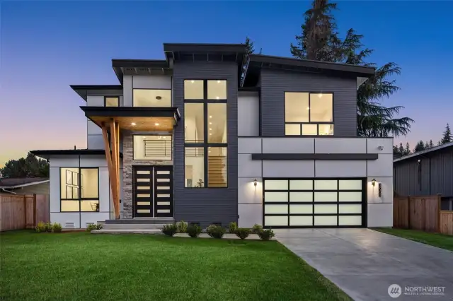 Modern exterior including vaulted entryway and glass garage door