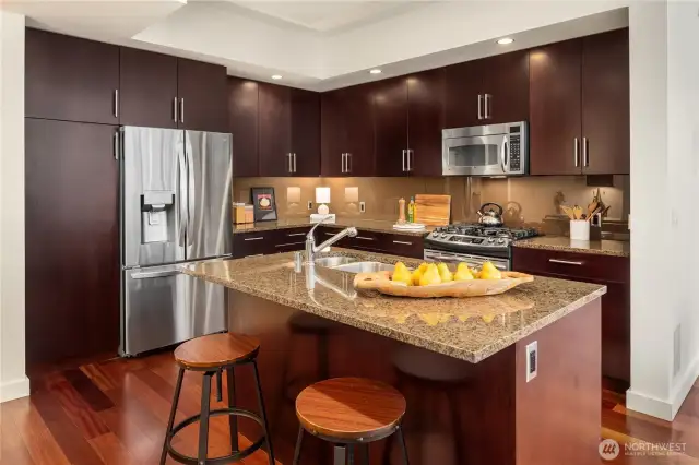 Floor to ceiling wood cabinetry with stainless appliances and gas cooking.