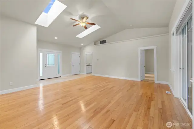 View from the dining area toward the front door, door to the garage, primary bedroom and laundry room