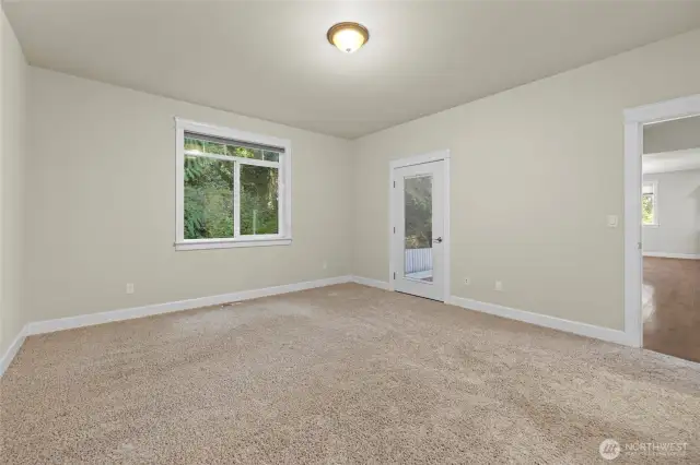 Additional view of primary bedroom looking toward exterior door leading to the covered deck