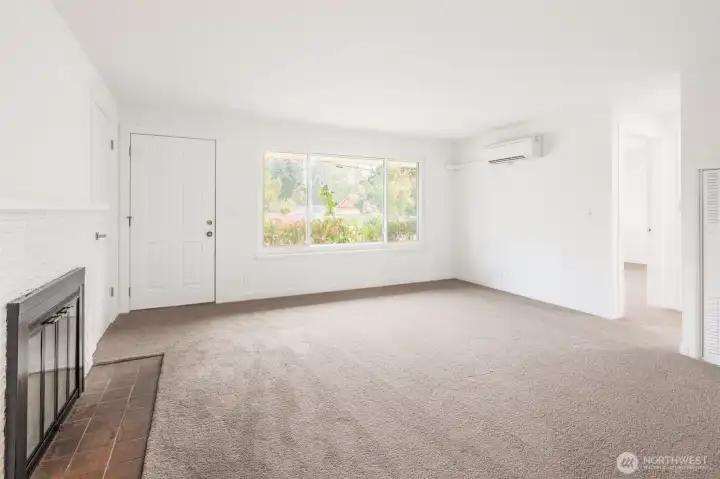 Comfortable front living space with new carpet, wood buring fireplace, and ductless mini split