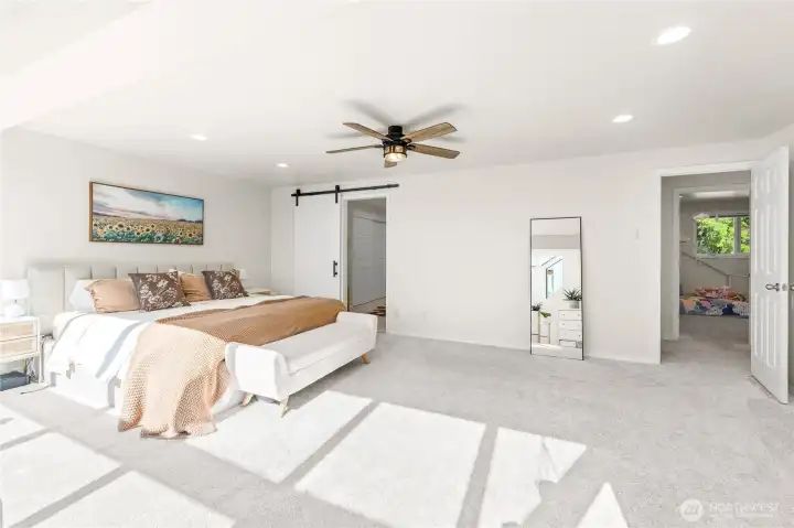 Primary bedroom with sliding barn door to en suite full bathroom and closet