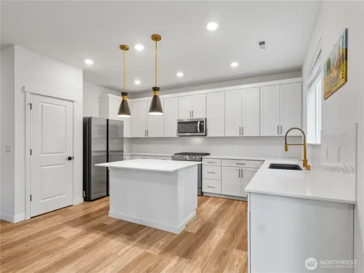 The kitchen has an island with room for seating and a pantry for additional storage. The stainless steel appliances all stay.