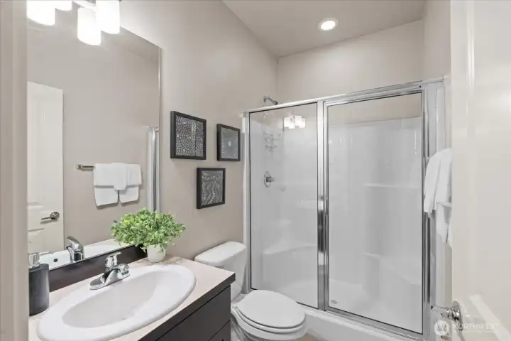 Bathroom downstairs featuring a large mirror and a glass-enclosed shower. Clean finishes and efficient layout.