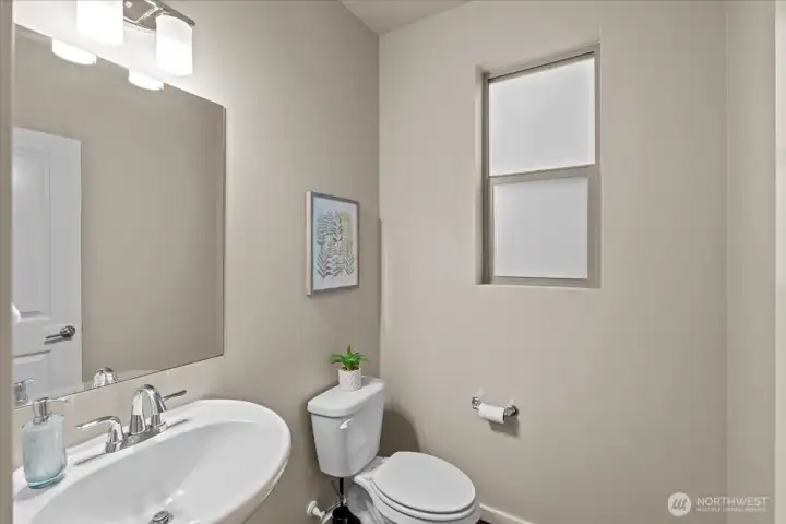 Bathroom featuring a pedestal-style sink and a window for natural light. Compact layout with neutral finishes.