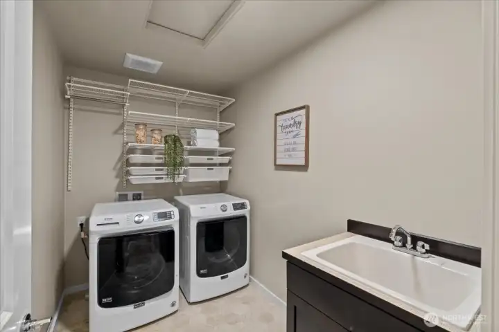 Laundry Room with side-by-side washer and dryer, utility sink, and built-in shelving. Organized space designed for everyday convenience.