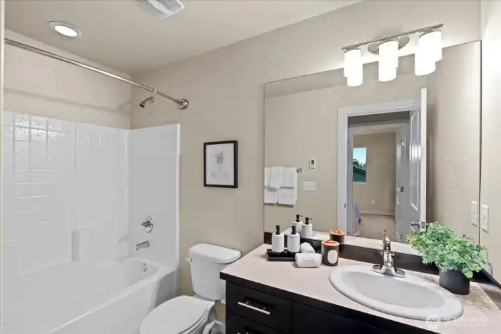 Bathroom with large mirror and tub/shower combination. Functional layout with bright overhead lighting.