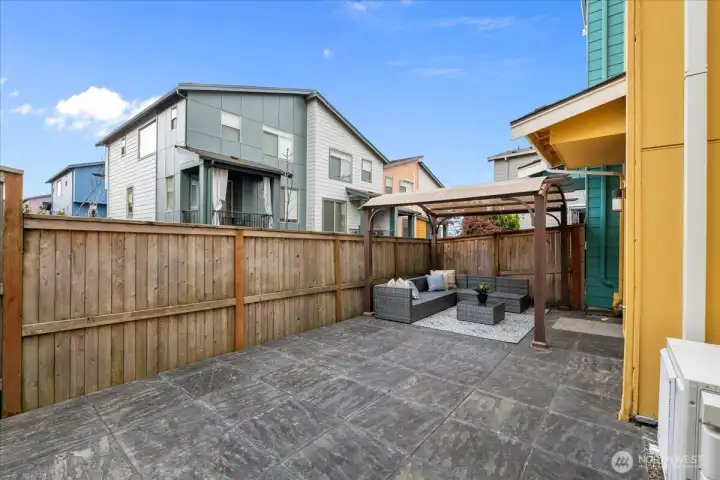 Fenced Backyard featuring a paved patio with a covered pergola and outdoor seating area. It provides a defined outdoor space for relaxing or entertaining.