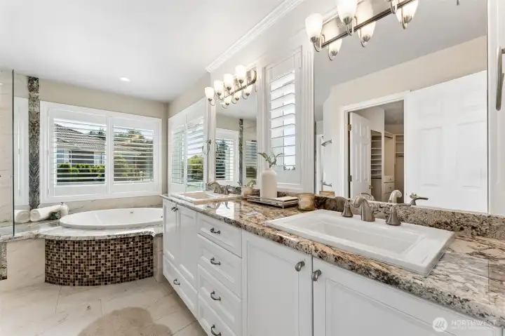 Remodeled primary bathroom with dual sinks, jetted tub, and walk-in shower