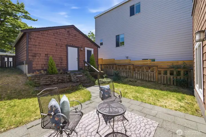 Charming back patio surrounded by lush greenery and garden beds for outdoor entertaining. Charming back patio surrounded by lush greenery and garden beds for outdoor entertaining.
